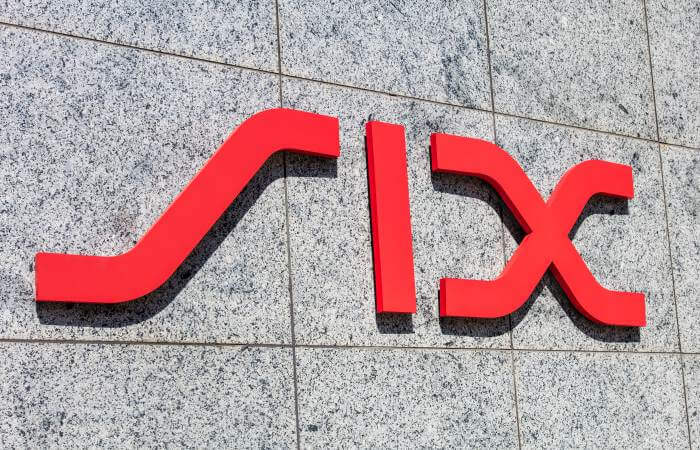 Das rote SIX Logo an einer Natursteinfassade